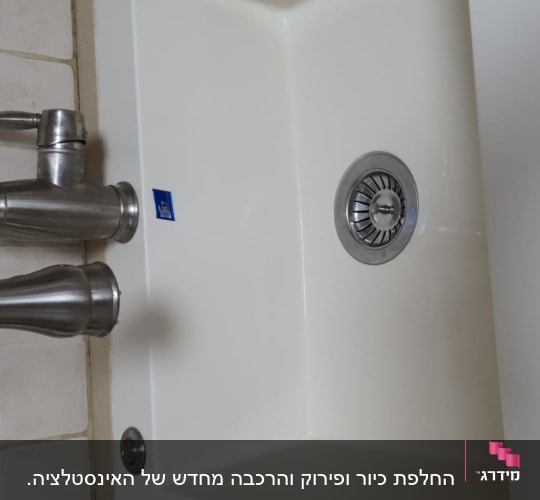 כיור לבן עם ברזים על משטח שיש